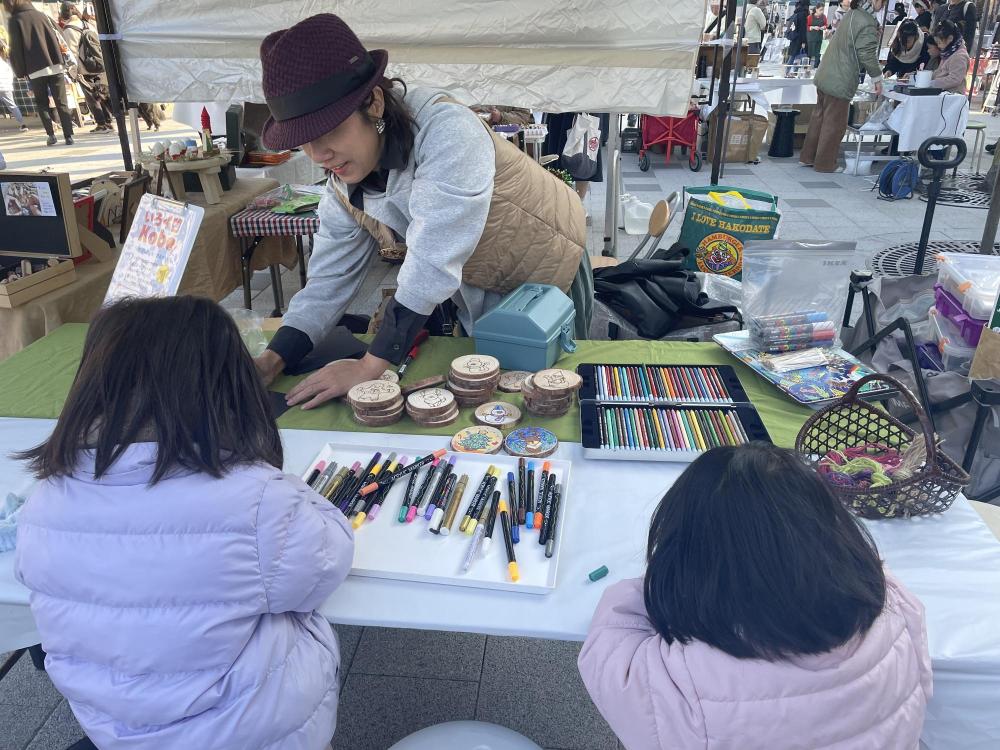 伊丹クリスマスマーケットで木のスライスでワークショップをする子供