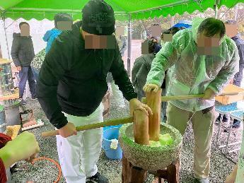 男性二人が餅をつぶす様子