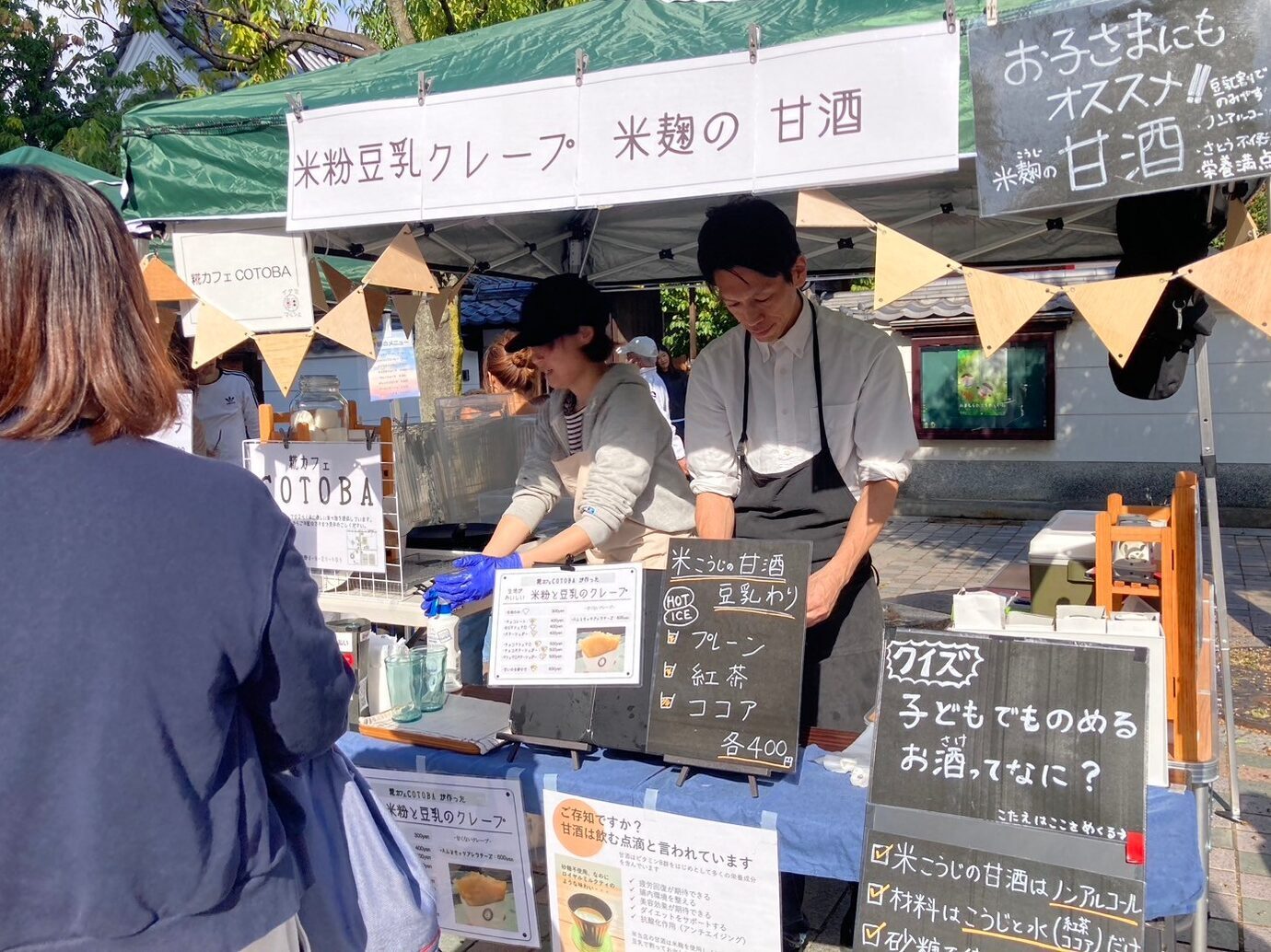 いたみあさまるしぇのおみせでかったしょうひんをまっているじょせい
