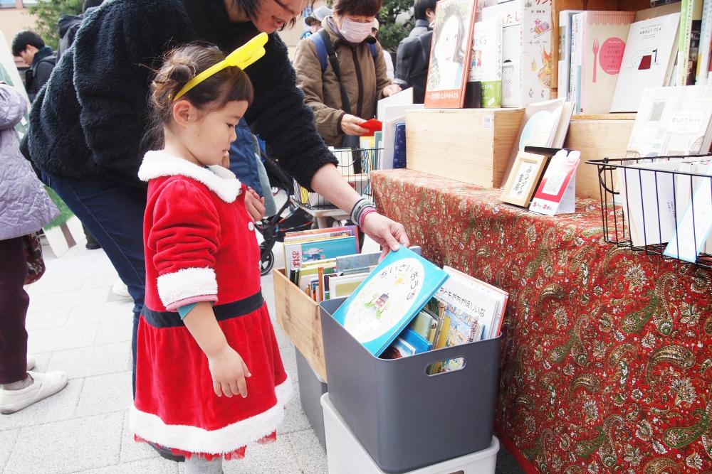 伊丹クリスマスマーケットでサンタの恰好をした子供が本を選ぶ