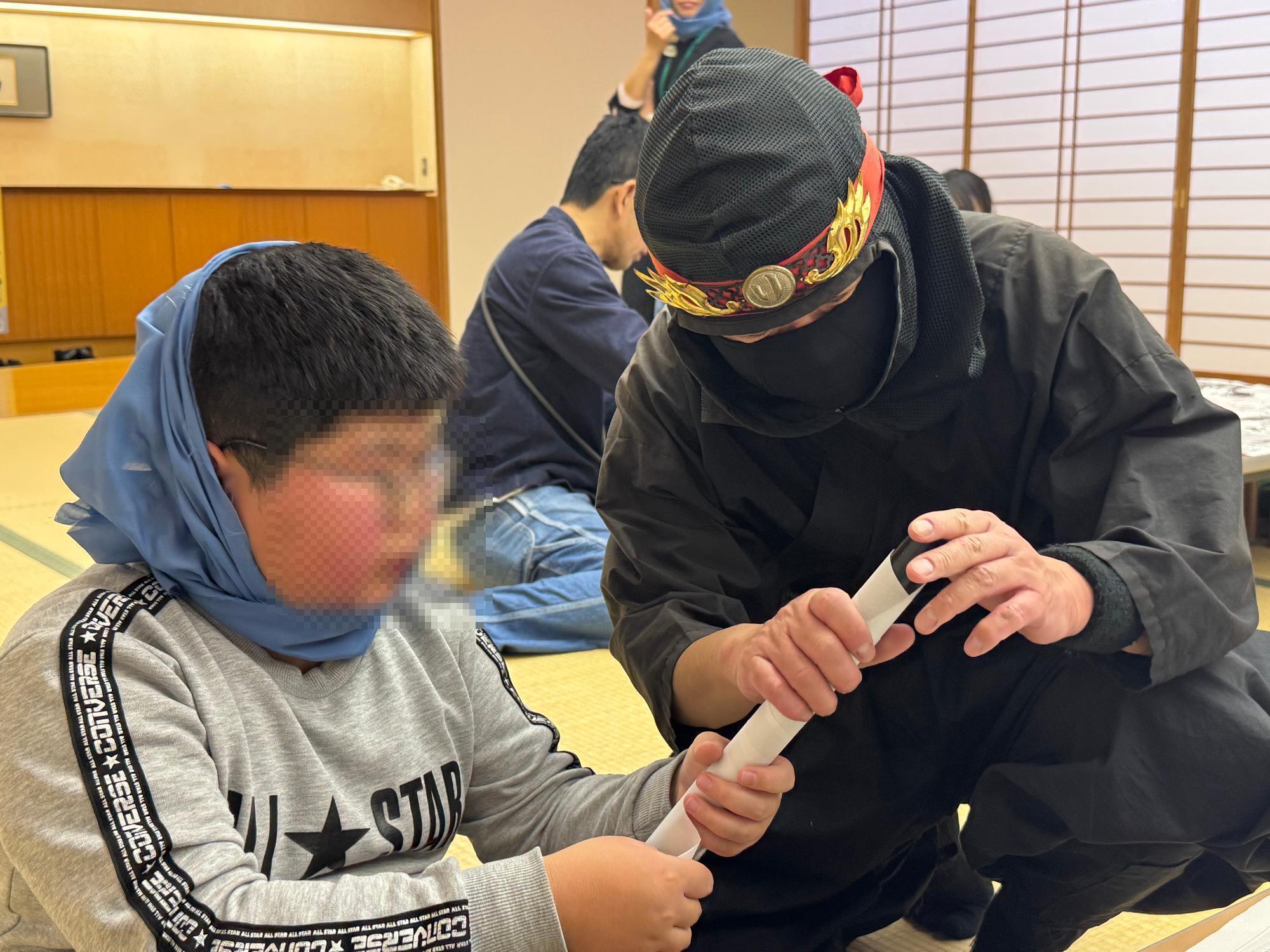 なりきり忍者イベントでりい忍者から巻物の暗号の書き方をおそわる子供