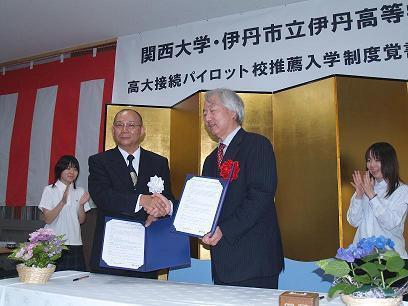 握手を交わす河田学長（右）と鶴田校長の写真